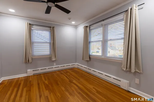a view of an empty room with a window and wooden floor