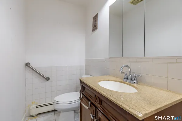 a bathroom with a granite countertop sink and a toilet