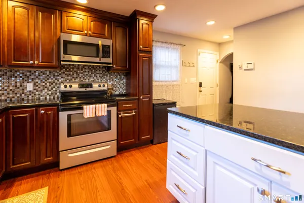 a kitchen with stainless steel appliances granite countertop wooden cabinets and a stove top oven