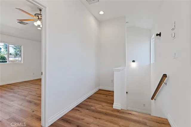 an empty room with wooden floor and ceiling fan