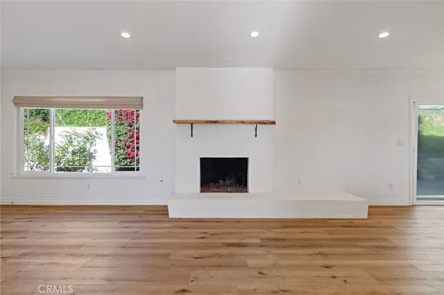 a view of an empty room with wooden floor and a fireplace