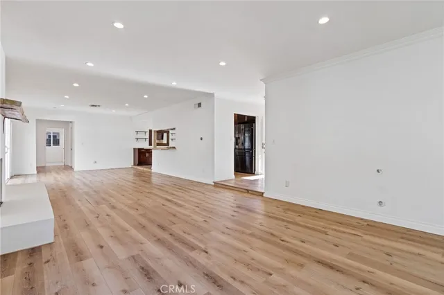 an empty room with wooden floor and a kitchen
