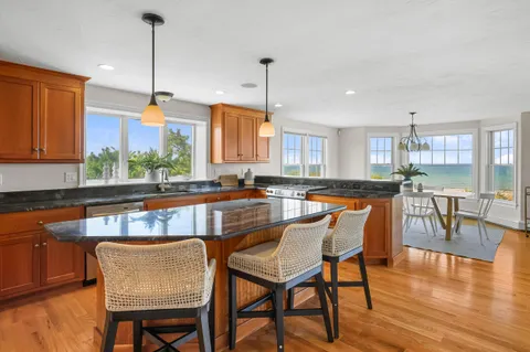 a kitchen with stainless steel appliances granite countertop a stove top oven a dining table and chairs with wooden floor