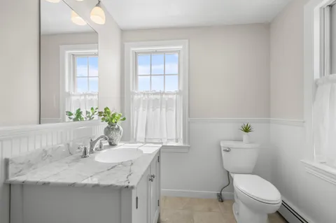 a bathroom with a granite countertop toilet a sink and a window
