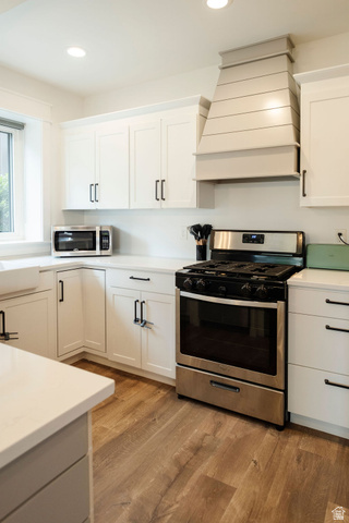 924 Country Lane Farmington, UT 84025 - Photo 53 of 91 Modern kitchen featuring a stainless steel range, custom range hood, recessed lighting, white cabinetry with dark hardware, and wood-finish flooring