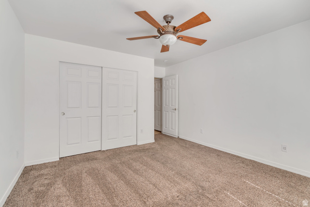 546 Wheatridge Road Tooele, UT 84074 - Photo 18 of 49 Spacious room featuring neutral carpeting, white walls, a ceiling fan with wood-finish blades, and a double sliding closet with panel doors
