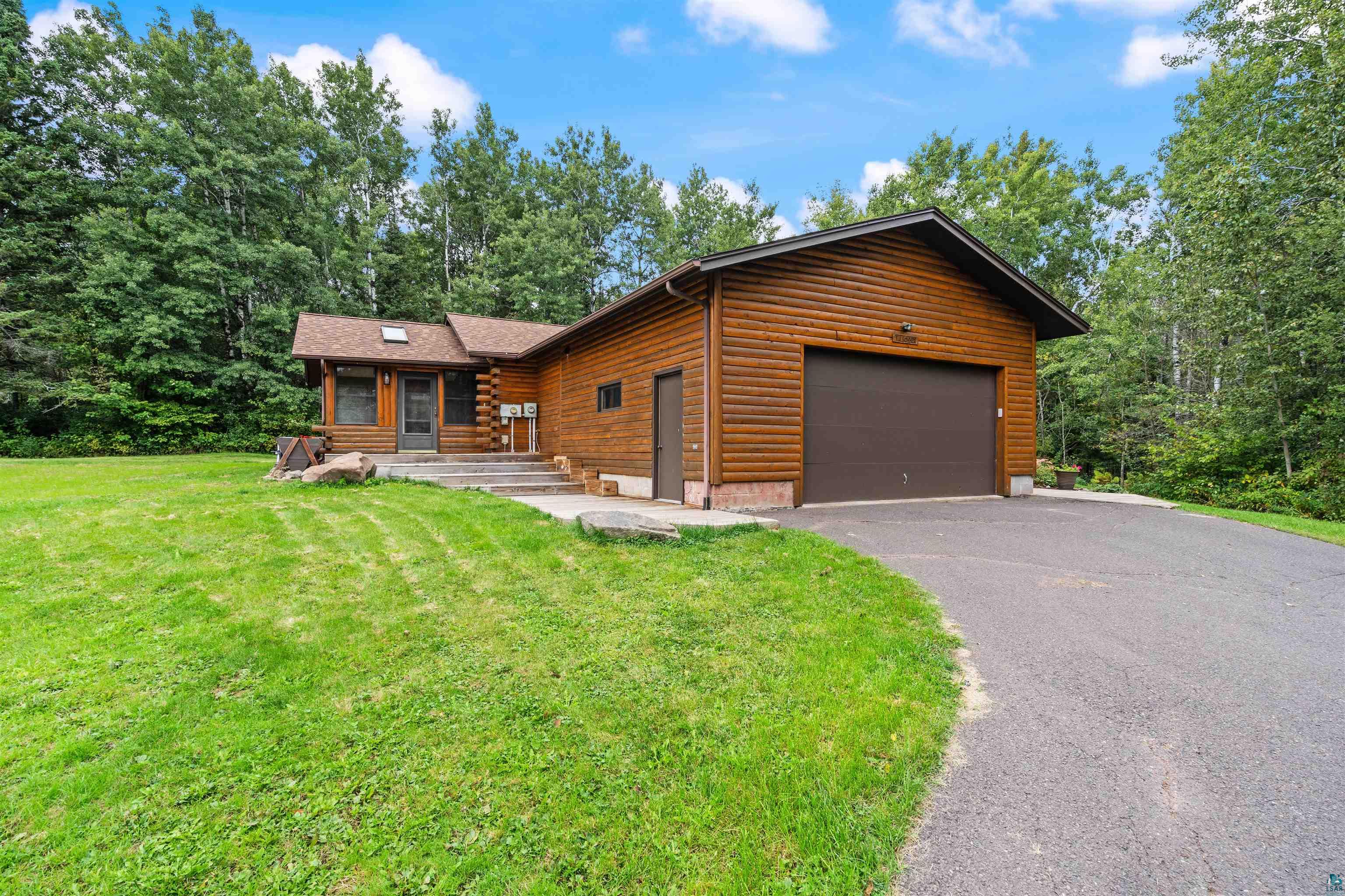 5373 Lester River Road Duluth, MN 55804 - Photo 1 of 39 Wood-sided exterior with an attached garage, paved driveway, and mature surrounding trees