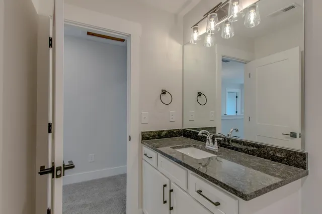 a bathroom with a granite countertop sink a mirror and a vanity