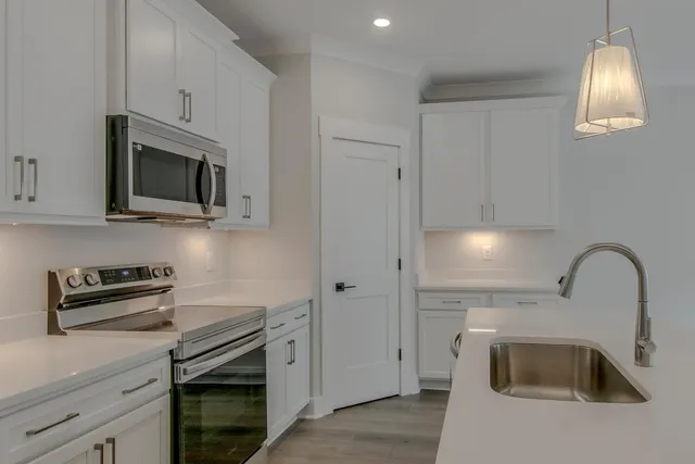 a kitchen with granite countertop a stove a sink and a microwave