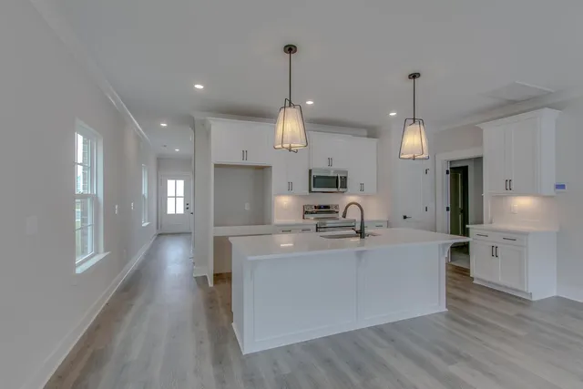 a large kitchen with stainless steel appliances kitchen island a large counter top and a wooden floors