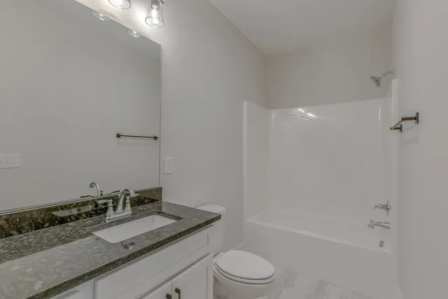a bathroom with a granite countertop sink a toilet and shower