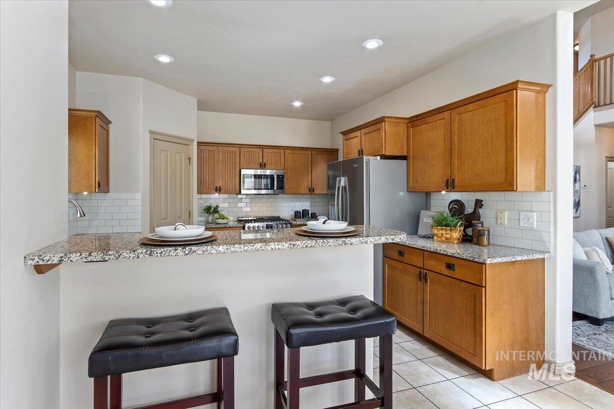 2274 Eastwood Road Twin Falls, ID 83301 - Photo 11 of 38 Kitchen featuring granite countertops, wood cabinetry, stainless steel appliances, white subway tile backsplash, and recessed lighting