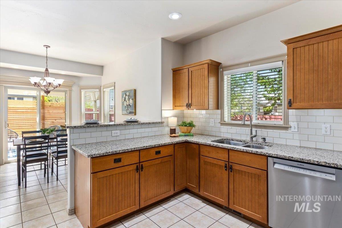 2274 Eastwood Road Twin Falls, ID 83301 - Photo 14 of 38 Kitchen featuring a double basin stainless steel sink, granite-finish countertops, subway tile backsplash, and light wood-finish cabinetry
