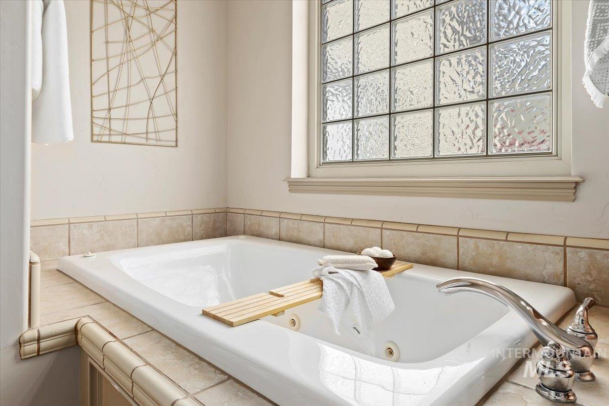 2274 Eastwood Road Twin Falls, ID 83301 - Photo 19 of 38 Built-in soaking tub featuring a chrome faucet, tile surround, and a privacy glass block window