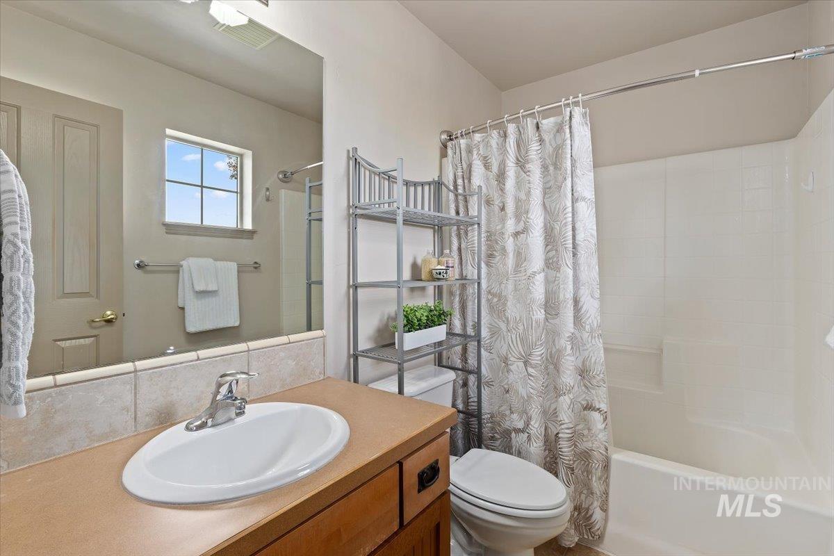 2274 Eastwood Road Twin Falls, ID 83301 - Photo 25 of 38 Bathroom featuring a single vanity with an oval sink, wood-finish cabinetry, and a tile backsplash