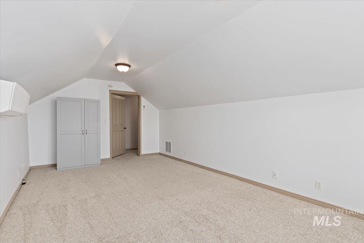 2274 Eastwood Road Twin Falls, ID 83301 - Photo 27 of 38 Carpeted attic space featuring sloped ceilings, a light-toned wood-finish door, and a built-in storage cabinet