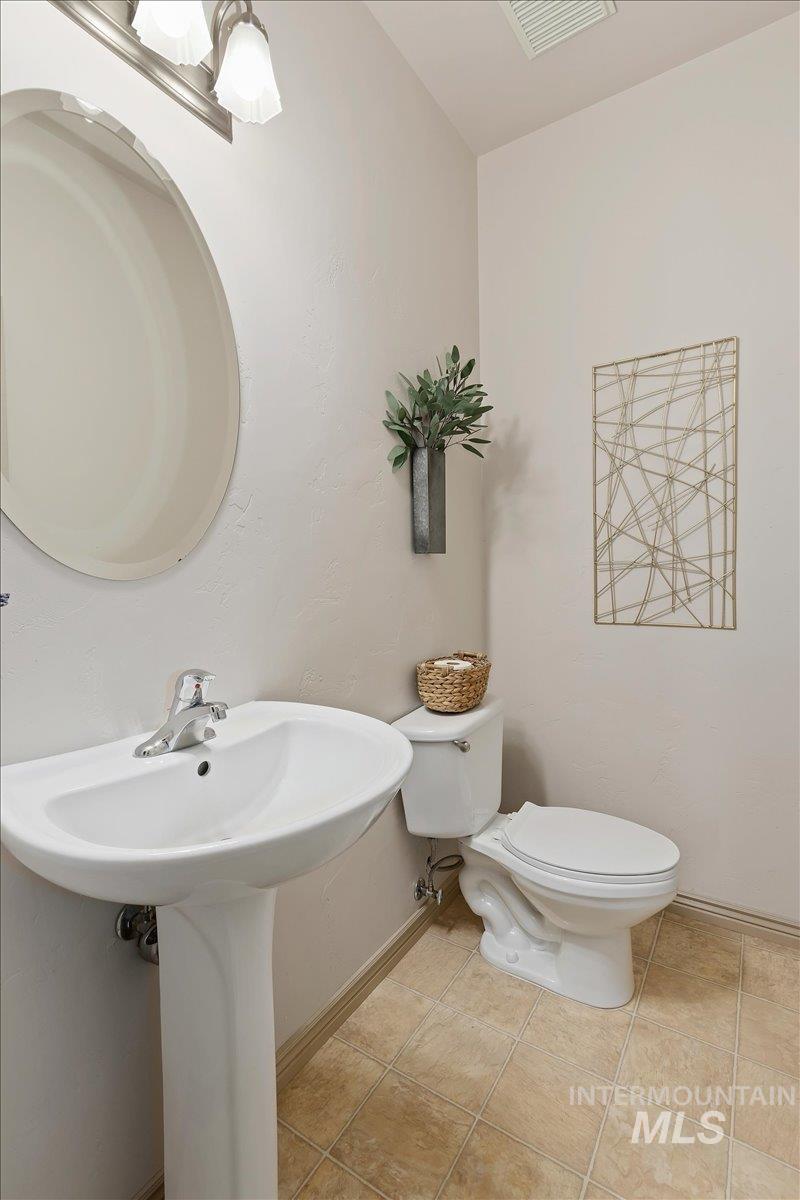 2274 Eastwood Road Twin Falls, ID 83301 - Photo 28 of 38 Pedestal sink with chrome faucet, circular mirror, and wall-mounted light fixture