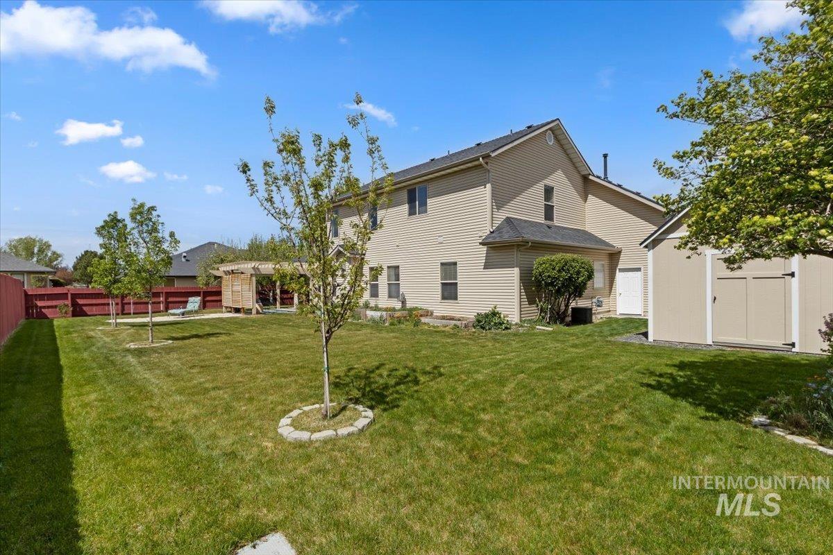 2274 Eastwood Road Twin Falls, ID 83301 - Photo 34 of 38 Spacious backyard featuring a manicured lawn, established trees, and a wooden pergola
