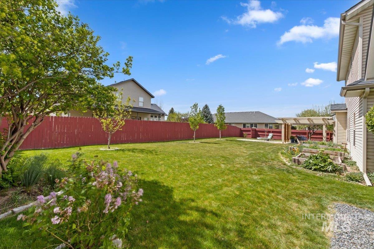 2274 Eastwood Road Twin Falls, ID 83301 - Photo 37 of 38 Spacious backyard featuring a vibrant red privacy fence, established perimeter trees, and a wooden pergola structure
