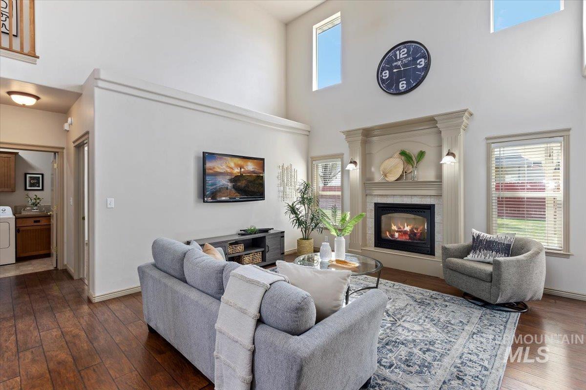 2274 Eastwood Road Twin Falls, ID 83301 - Photo 7 of 38 Living room featuring a vaulted ceiling with high transom windows, a fireplace with a decorative mantel and sconce lighting, and wood-finish flooring