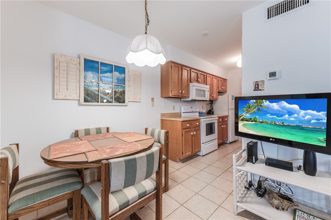 622 Beach Access Road, Unit 225 Port Aransas, TX 78373 - Photo 13 of 21 a kitchen with stainless steel appliances kitchen island granite countertop a sink a stove a table and chairs