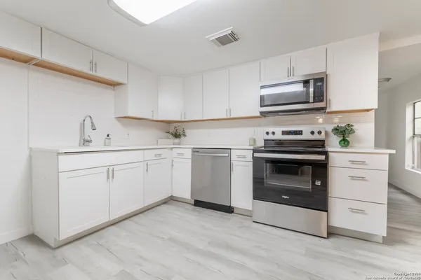 a kitchen with white cabinets stainless steel appliances and sink