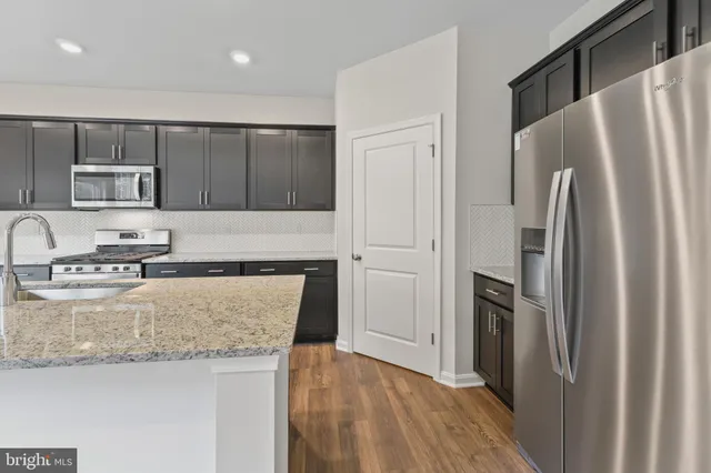 a kitchen with granite countertop a refrigerator and a stove top oven