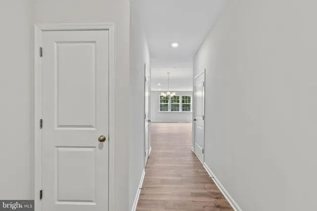 a view of a hallway with wooden floor and a bathroom