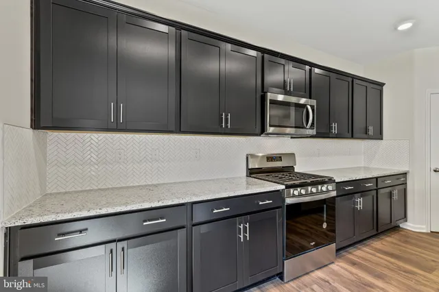 a kitchen with granite countertop stainless steel appliances wooden cabinets a stove and a sink