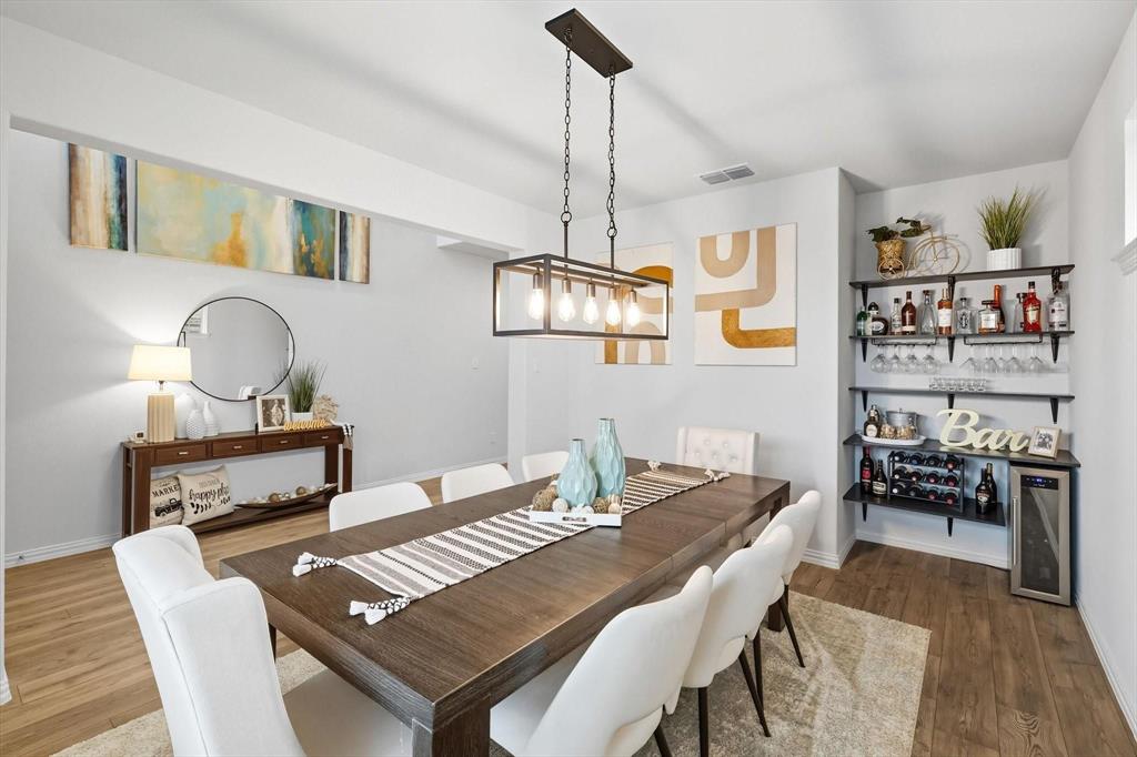 1724 Wassel Road Fort Worth, TX 76052 - Photo 5 of 24 Dining area featuring wood-finish flooring, a contemporary chandelier, a built-in beverage bar with shelving, a recessed wall niche, and a console table