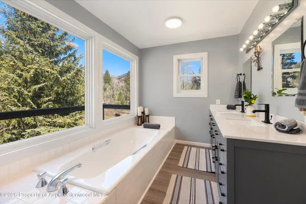 a bathroom with a sink a large mirror a bathtub and next to a window