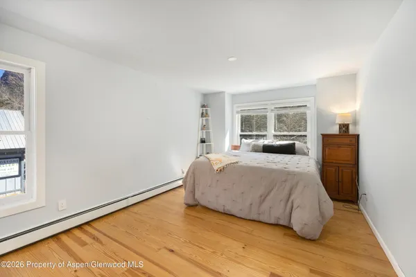 a bedroom with a bed windows and a night stand