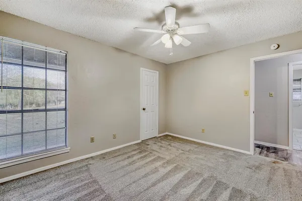 an empty room with windows and fan