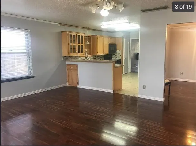 an open kitchen with wooden floor and a refrigerator