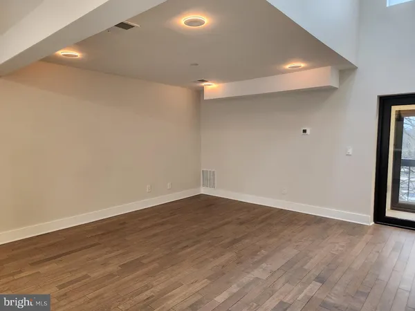 an empty room with wooden floor fireplace and windows
