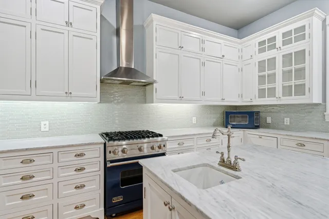 a kitchen with granite countertop a stove a sink and dishwasher with white cabinets