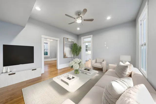 a living room with furniture a flat screen tv and a large window