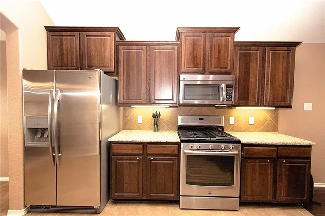 a kitchen with granite countertop a stove and a refrigerator with wooden floor