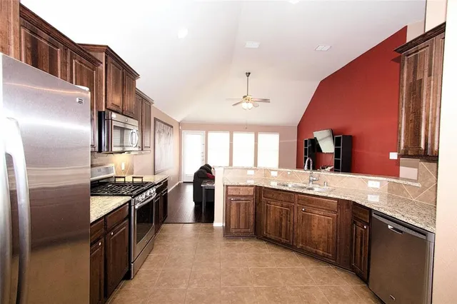 a kitchen with stainless steel appliances granite countertop a stove a sink dishwasher and a refrigerator