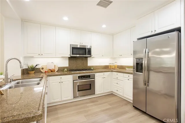 a kitchen with stainless steel appliances granite countertop a stove a sink and a refrigerator