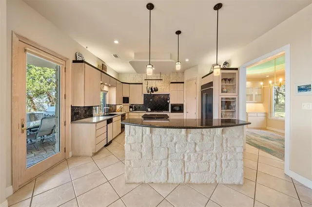 a large kitchen with kitchen island a large counter top a stove a sink and a chandelier