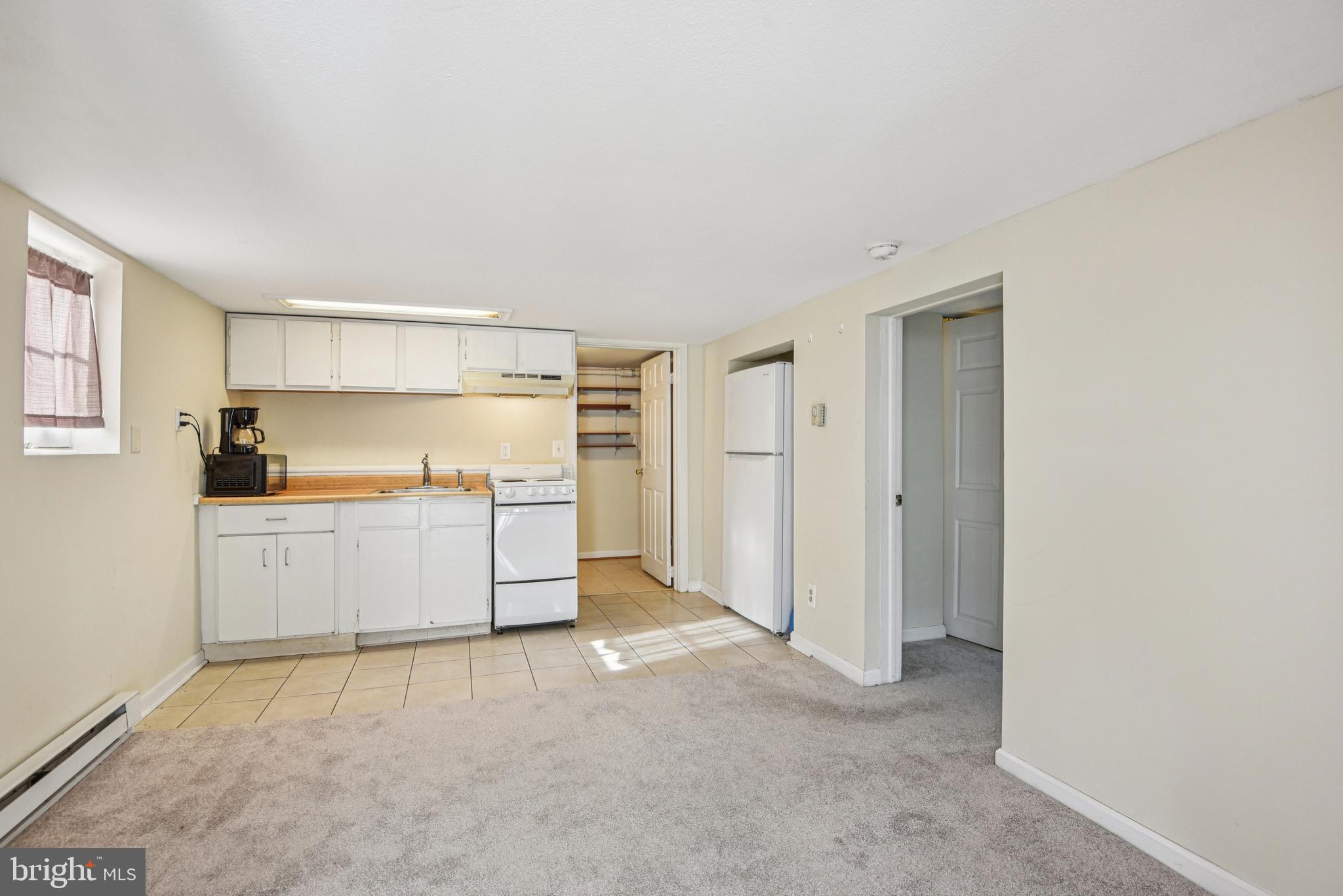 209 Locust Street, Unit B Frederick, MD 21703 - Photo 4 of 14 a kitchen with granite countertop a refrigerator and white cabinets