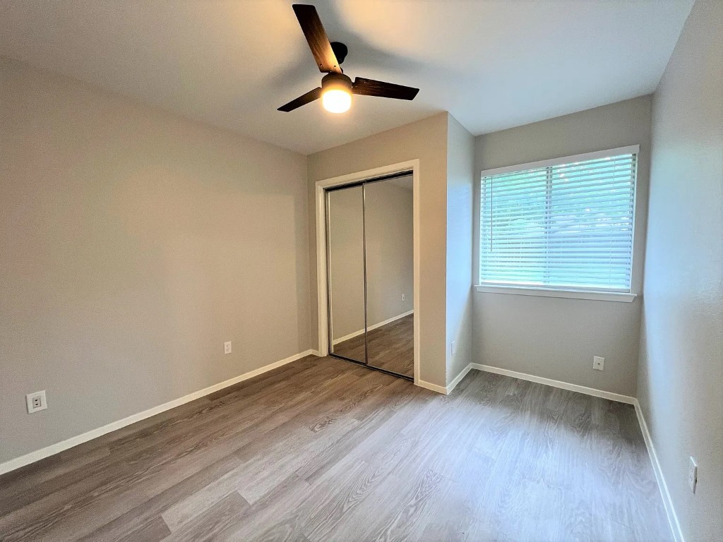 12214 Thompkins Drive, Unit B Austin, TX 78753 - Photo 13 of 13 Unfurnished bedroom with light wood-style flooring, a ceiling fan, and a closet