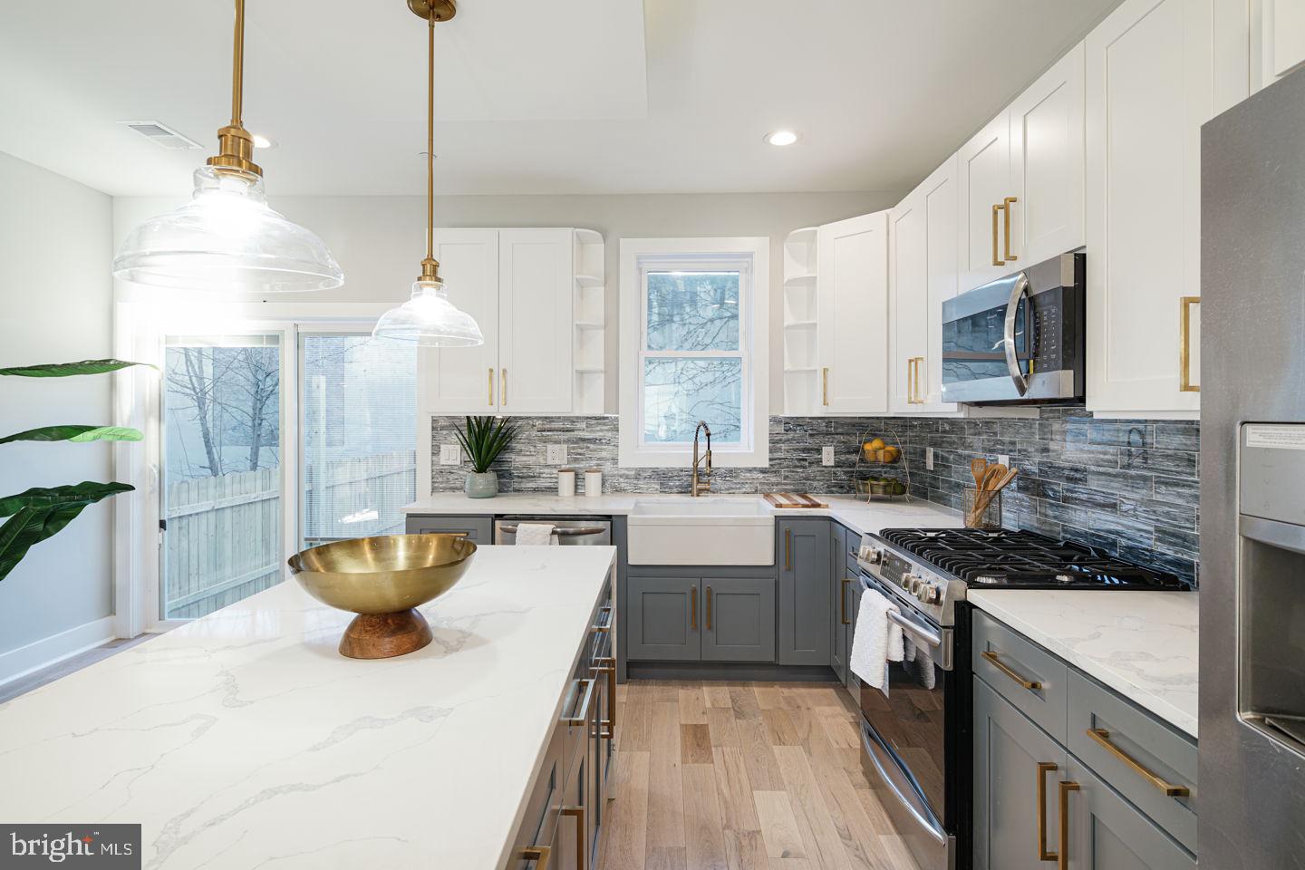 1434 Hope Street Philadelphia, PA 19122 - Photo 1 of 37 a kitchen with stainless steel appliances kitchen island granite countertop a sink a stove a microwave a center island and cabinets
