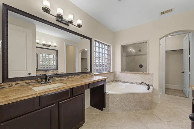 a bathroom with a granite countertop sink a large mirror and a bathtub with shower