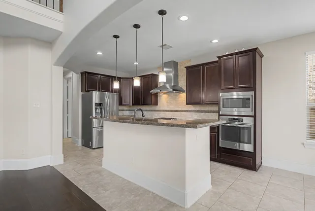 a kitchen with stainless steel appliances granite countertop a refrigerator a sink a stove and a refrigerator