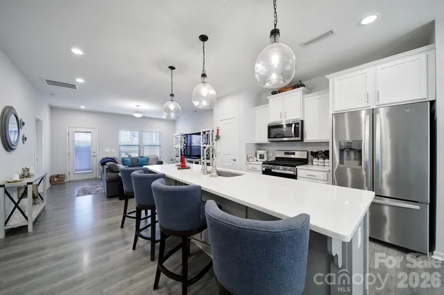 a kitchen with stainless steel appliances a dining table chairs stove and refrigerator