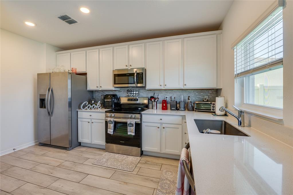 3986 Willowbrook Drive Edgewater, FL 32141 - Photo 14 of 57 a kitchen with refrigerator a sink a stove a microwave and cabinets