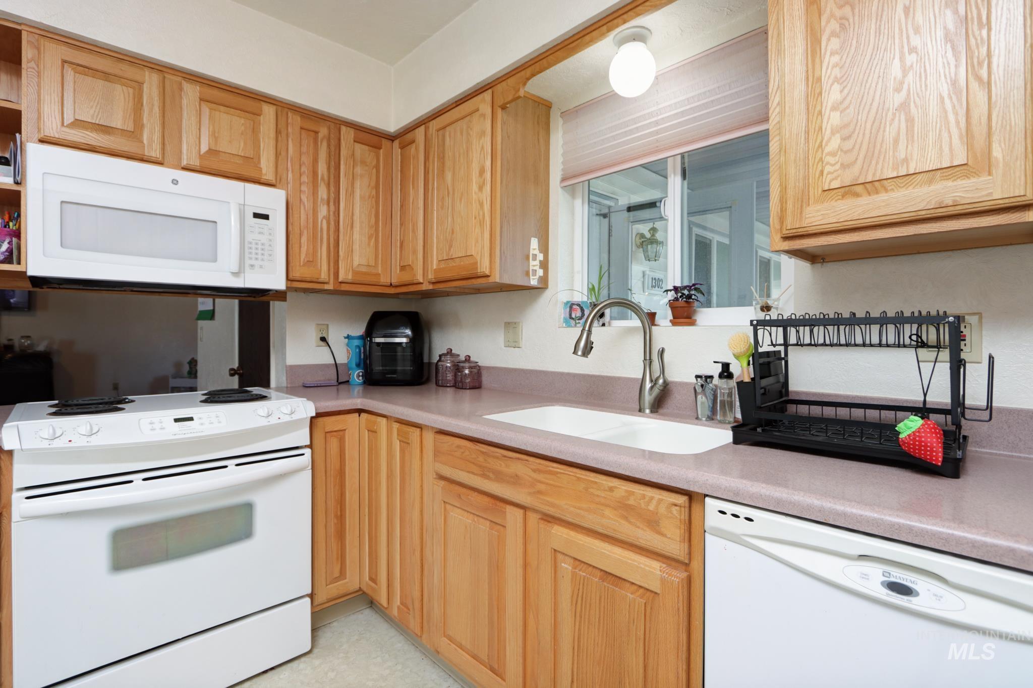 1302 Southwest 12th Street Ontario, OR 97914 - Photo 11 of 35 Kitchen with white appliances, light countertops, and light wood finish cabinetry