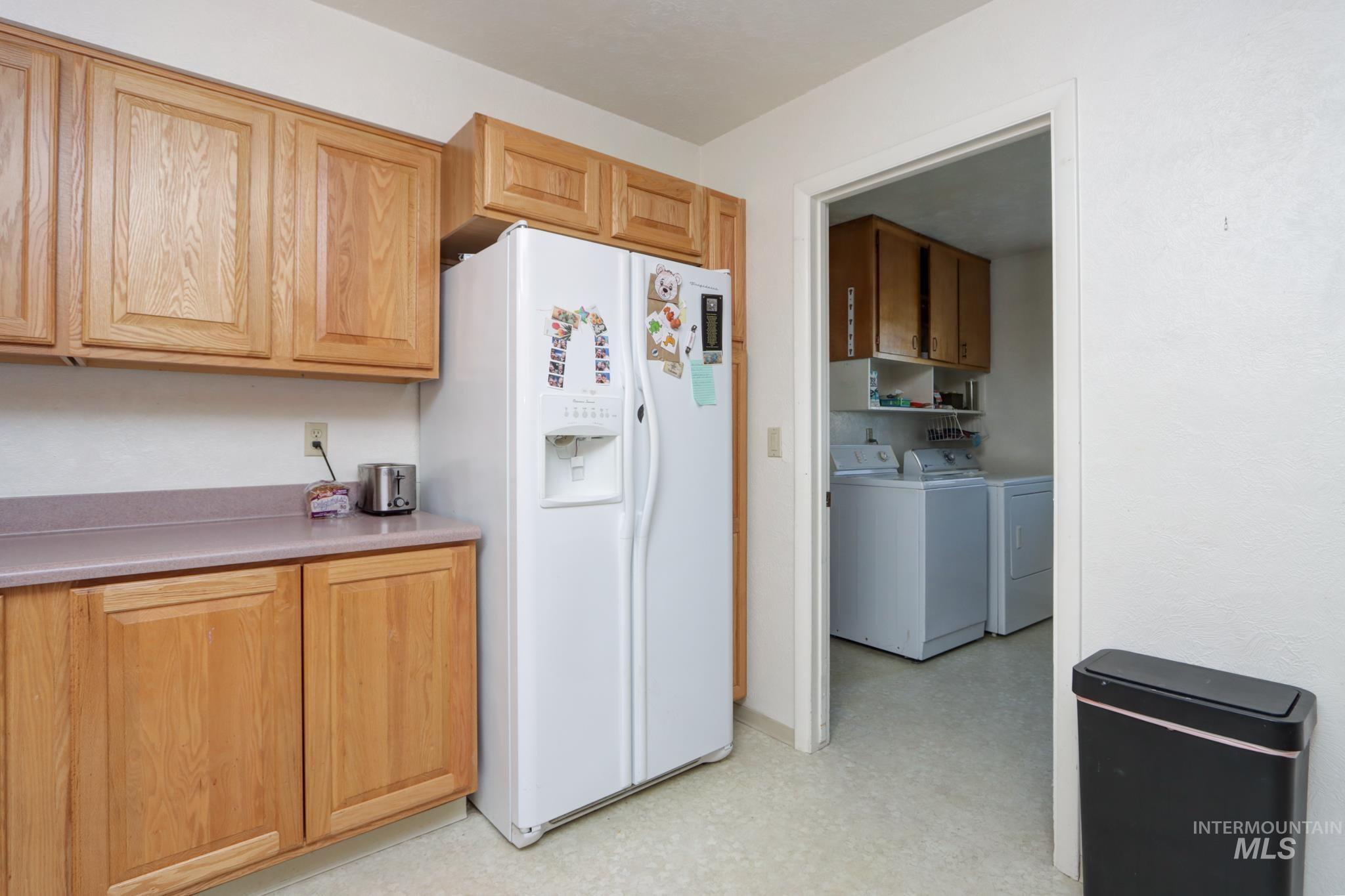 1302 Southwest 12th Street Ontario, OR 97914 - Photo 12 of 35 Kitchen with white fridge with ice dispenser, light floors, light countertops, and separate washer and dryer